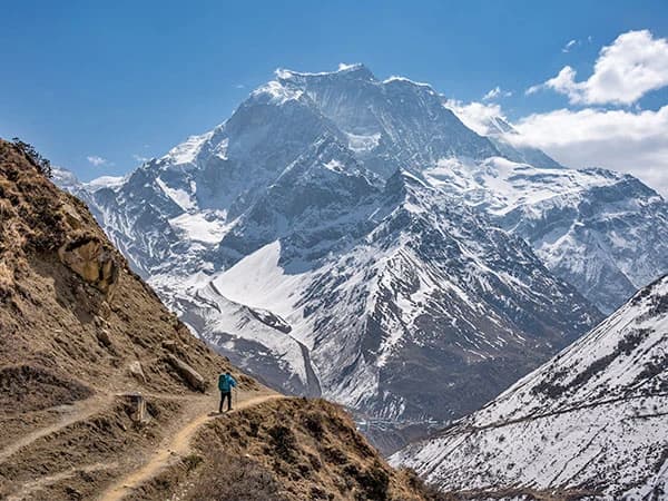 Solo hiker on the way to Dharmasala after crossing the Larkya La with the giant Annapurna 2 in the distance