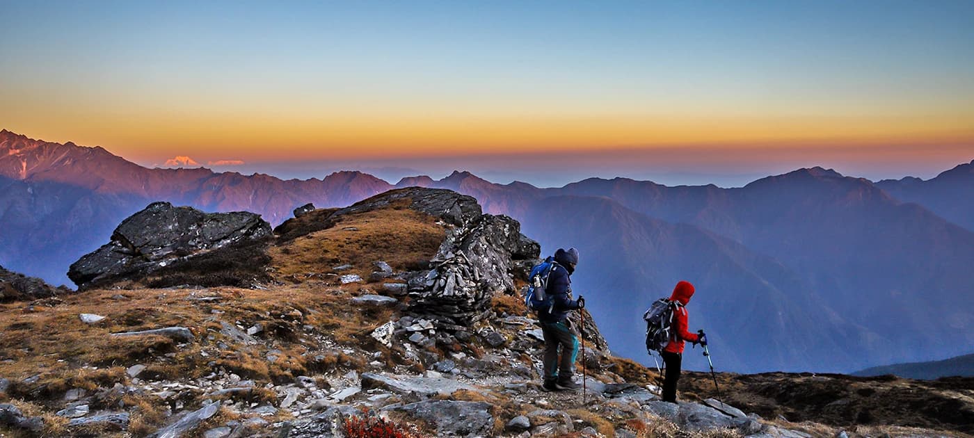 Two hikers on a panoramic ridge at sunrise