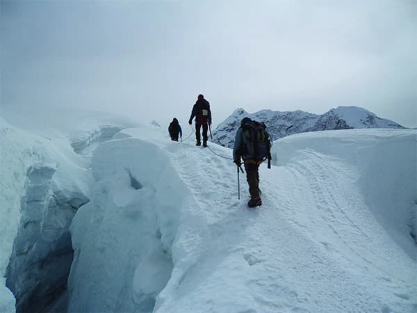 3 mountaineers on a glacial walk beside a creavase towards Island Peak summit from Crampon Point